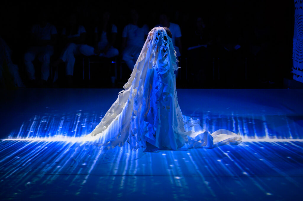 An image of a person draped in fabric and lit by a blue light.
