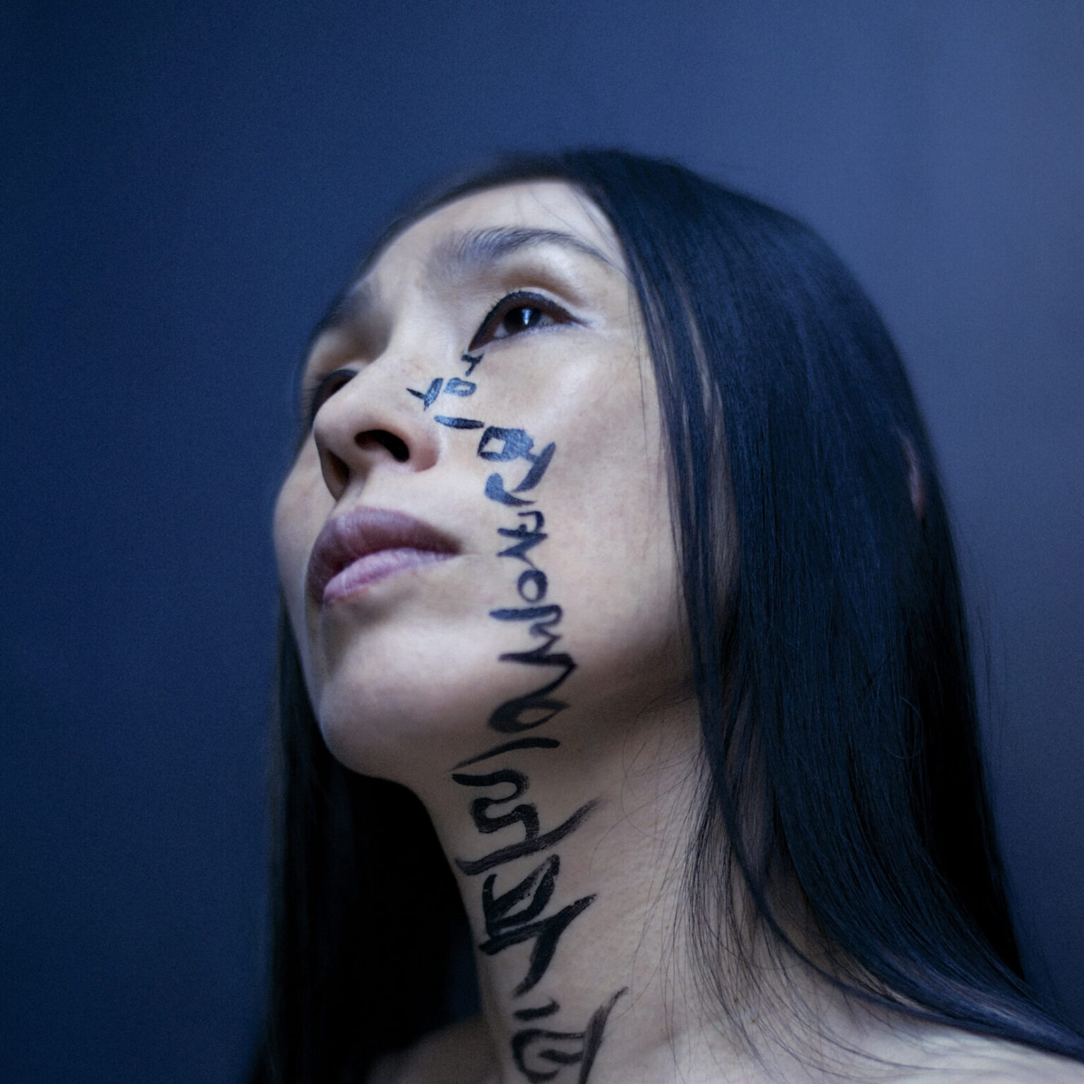 A portrait of a person with script down the cheek to the chest.