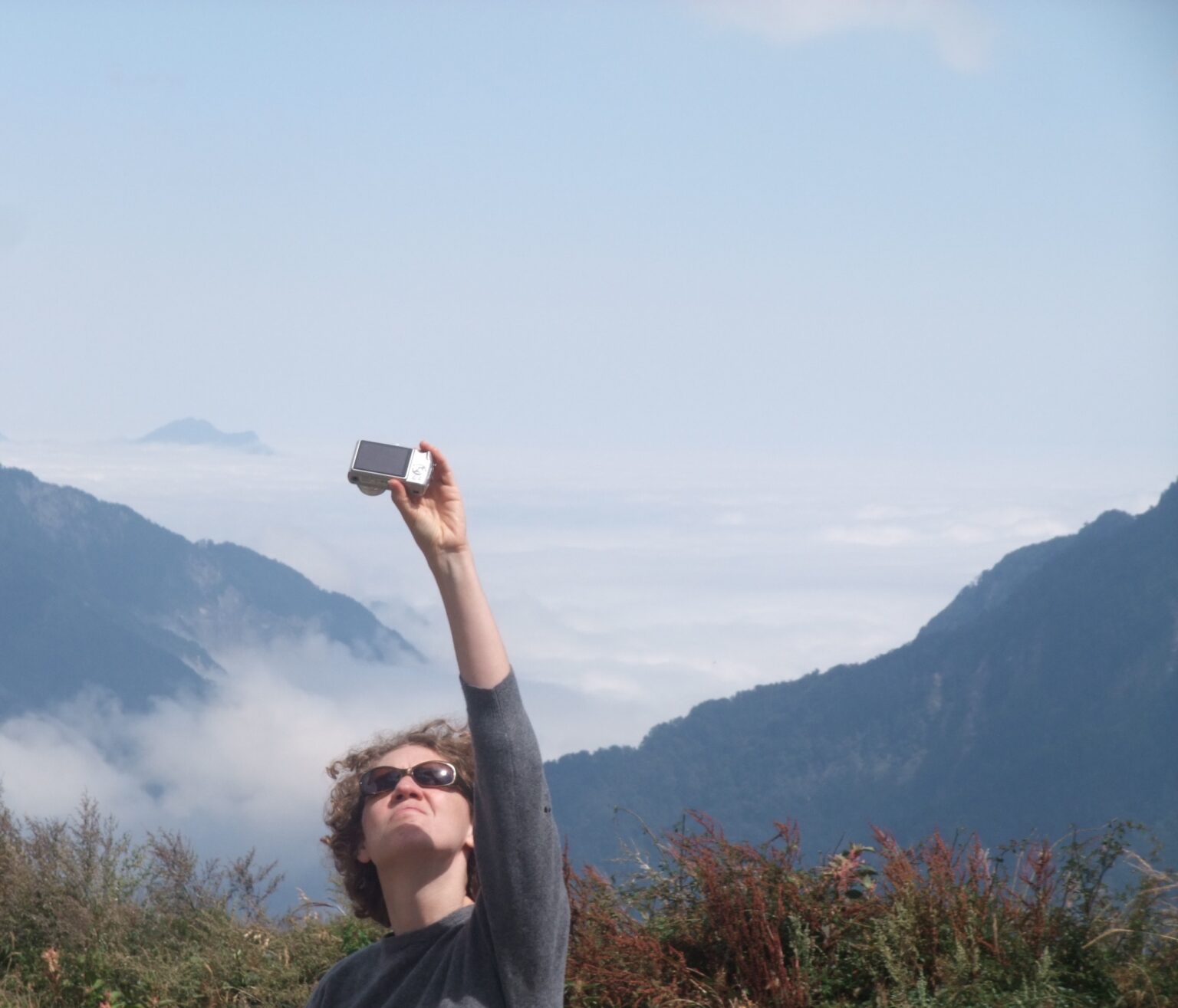 A person in a landscape holding a camera toward themselves.