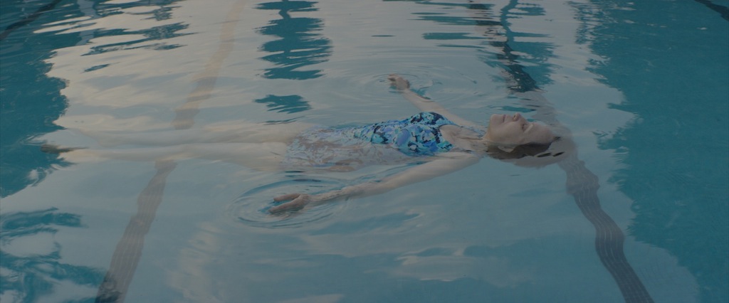 A person floating in a pool perpendicular to the racing lane lines.