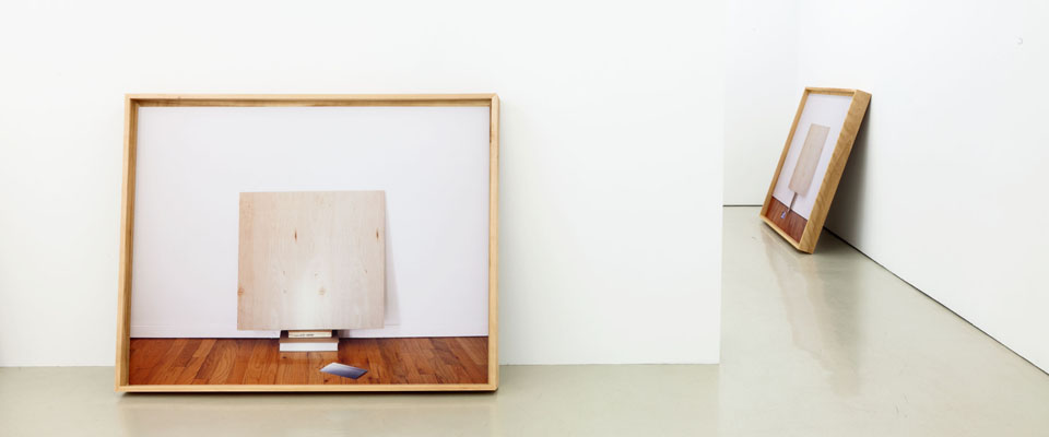 Two framed artworks leaning against the wall in a gallery.