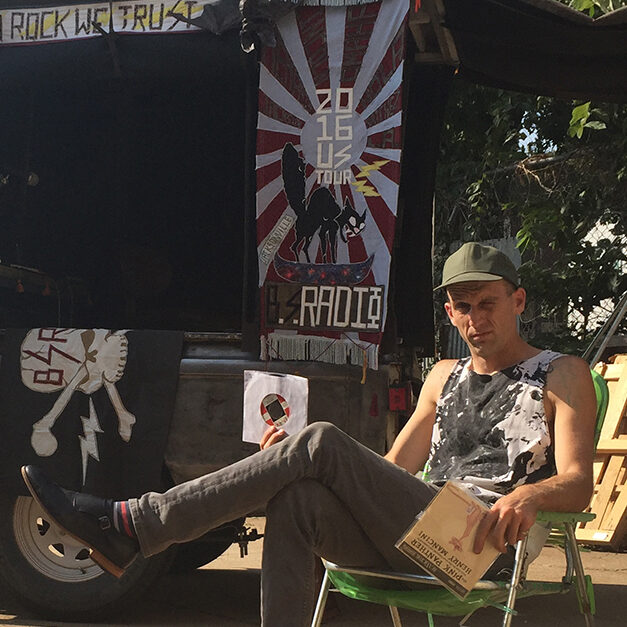 Joshua sitting outside in front of a portable radio station built into a trailer