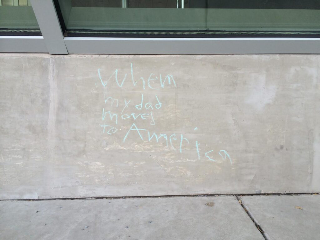 Words written in chalk on a low concrete wall.