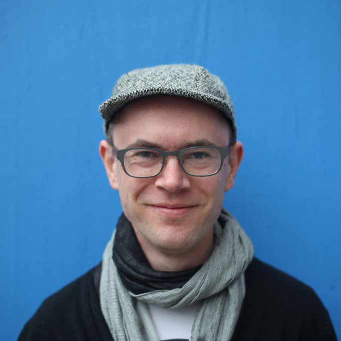 A portrait of a person against a blue background.