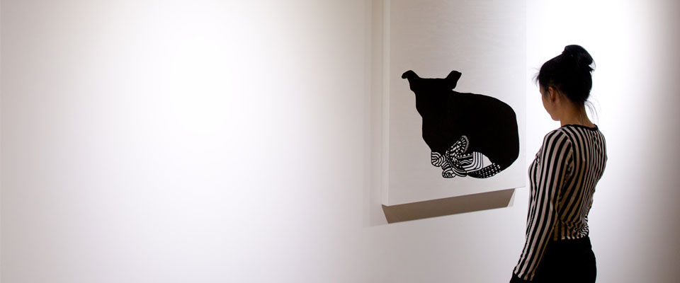 A person looking at a painting hung on a white wall of an animal.