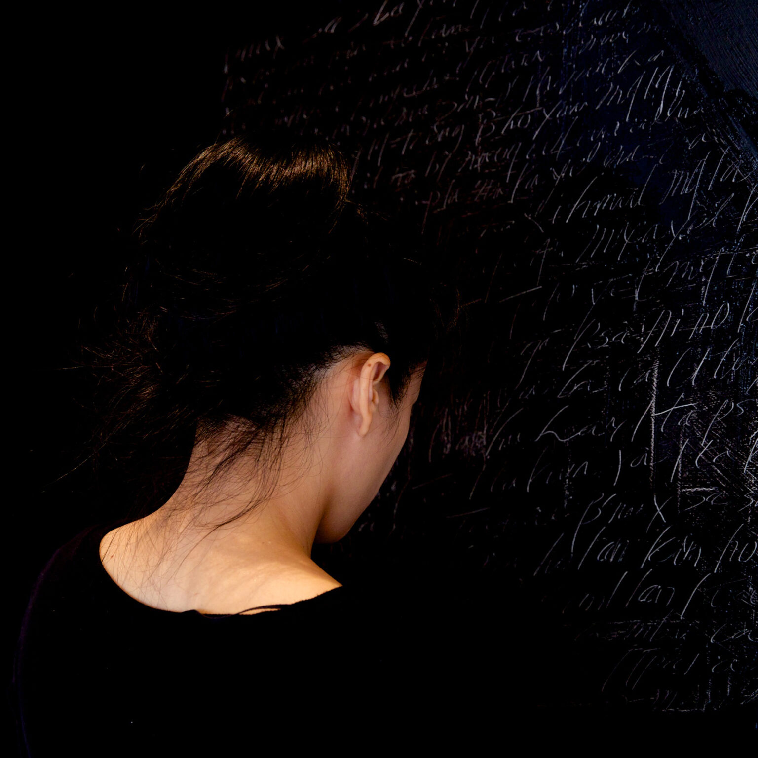 The back of a person's head against a dark background.