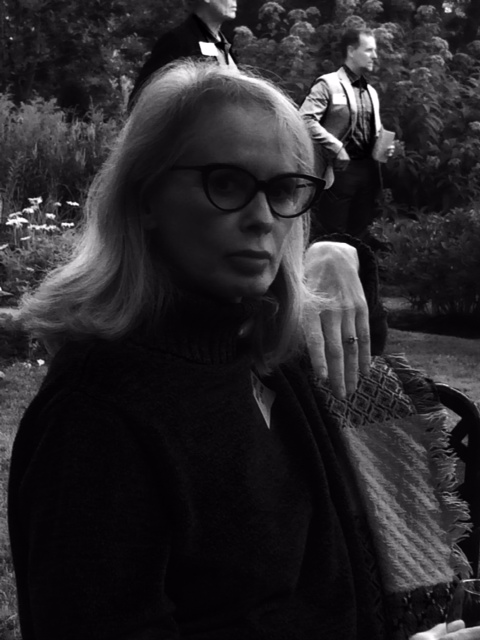 A portrait of a person sitting in a chair.