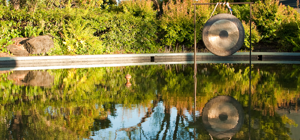 A gong suspended over a still pool.