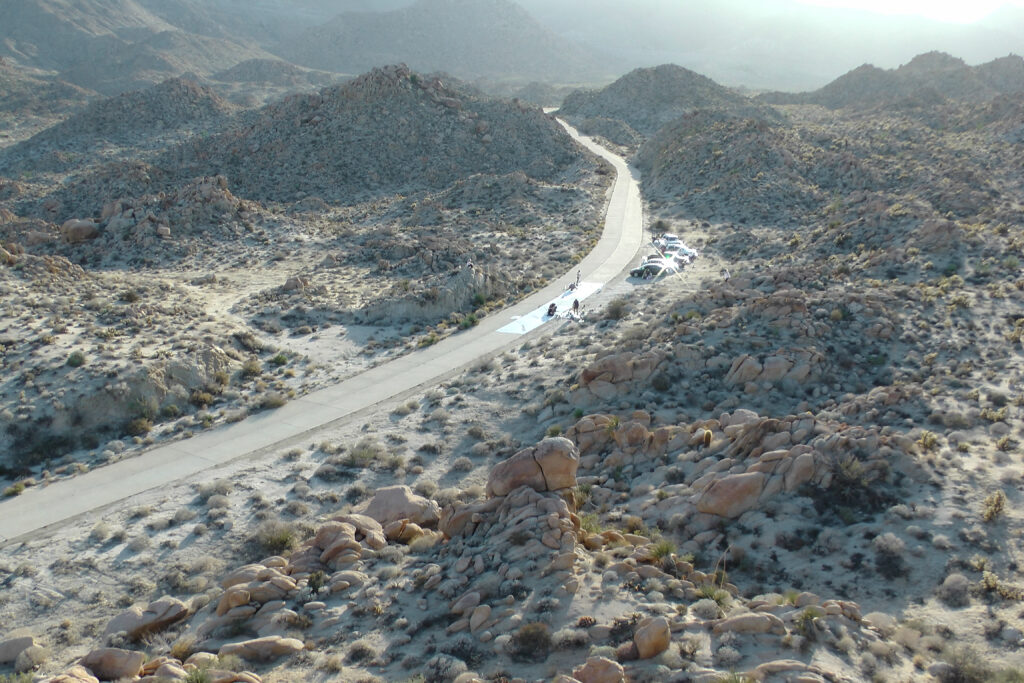 A desert landscape with people working in the road.