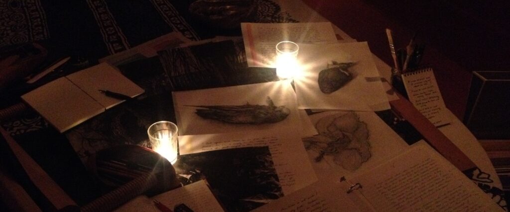 Illustrations and writing laid out on a candle-lit table.