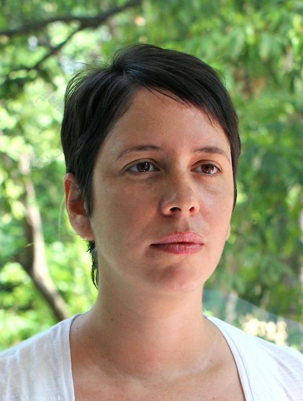 A portrait of a person against a leafy green background.