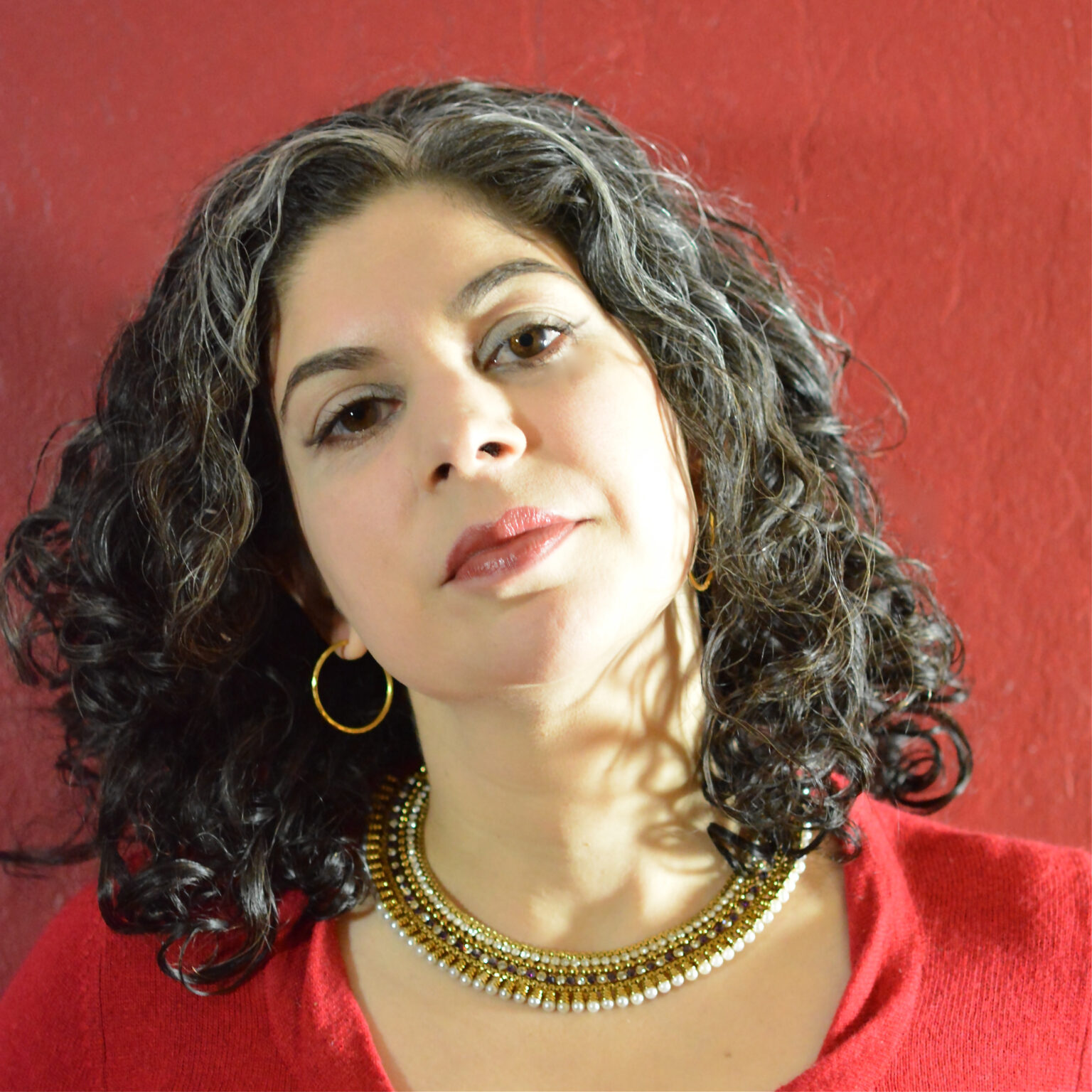 A portrait of a person against a red wall.