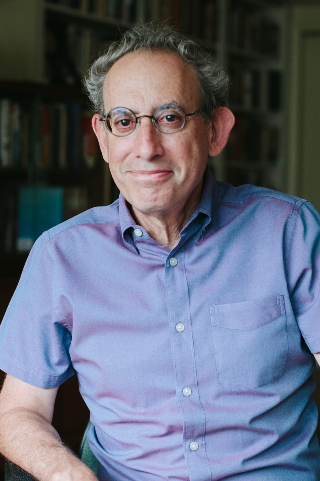 A portrait of a person in front of bookshelves.