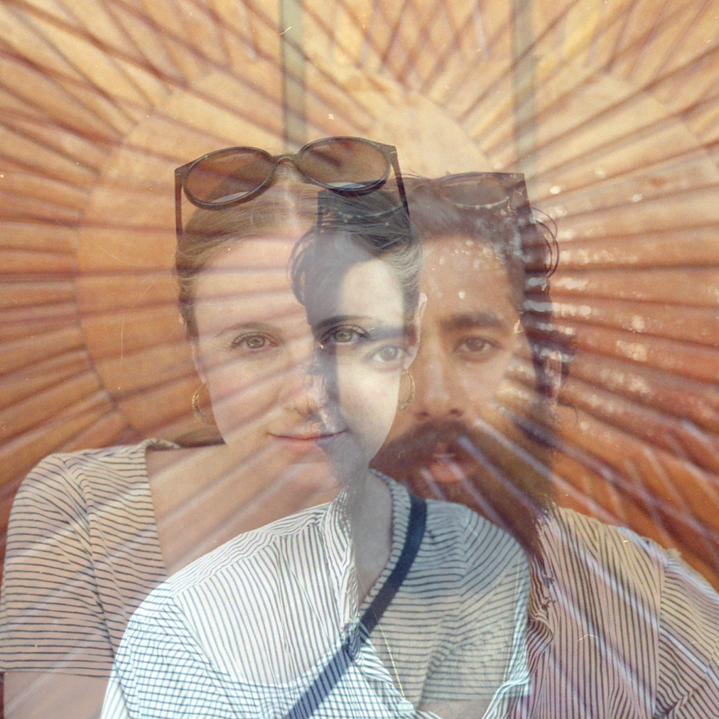 Two portraits against the background of a sun design superimposed.