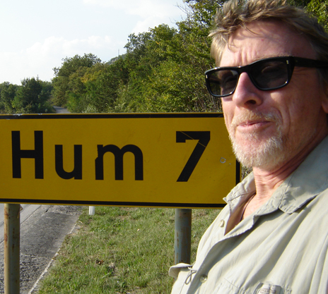 A person standing next a yellow sign on the side of the road.