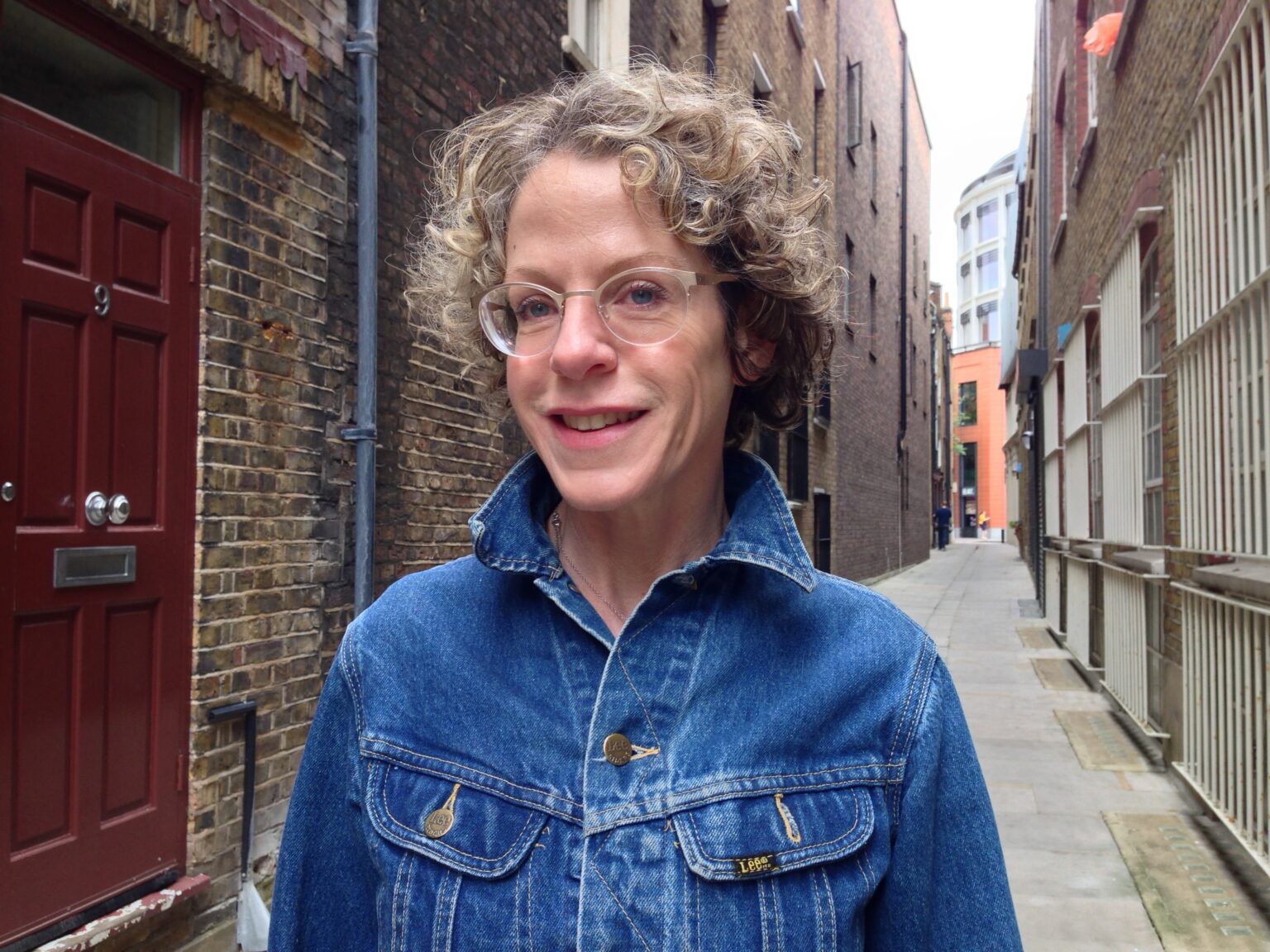 A portrait of a person in an alleyway lined with brick buildings.