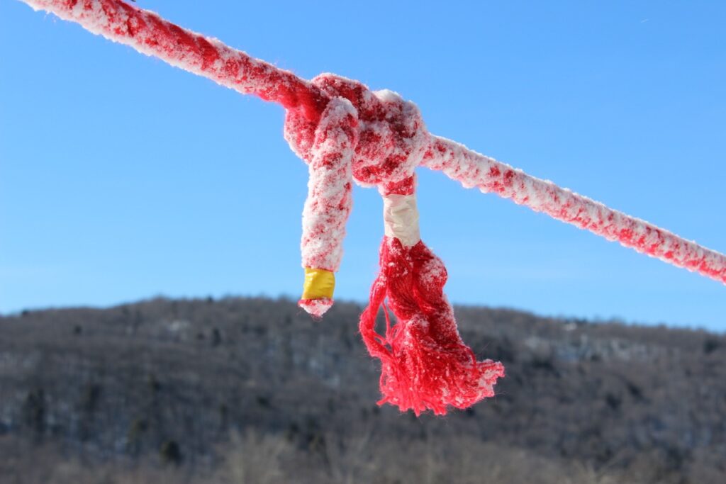 A knotted red rope against a background of hill and sky.