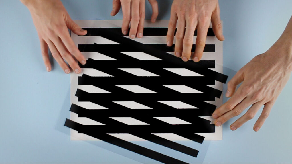 Two sets of hands touching geometric patterns on a table.