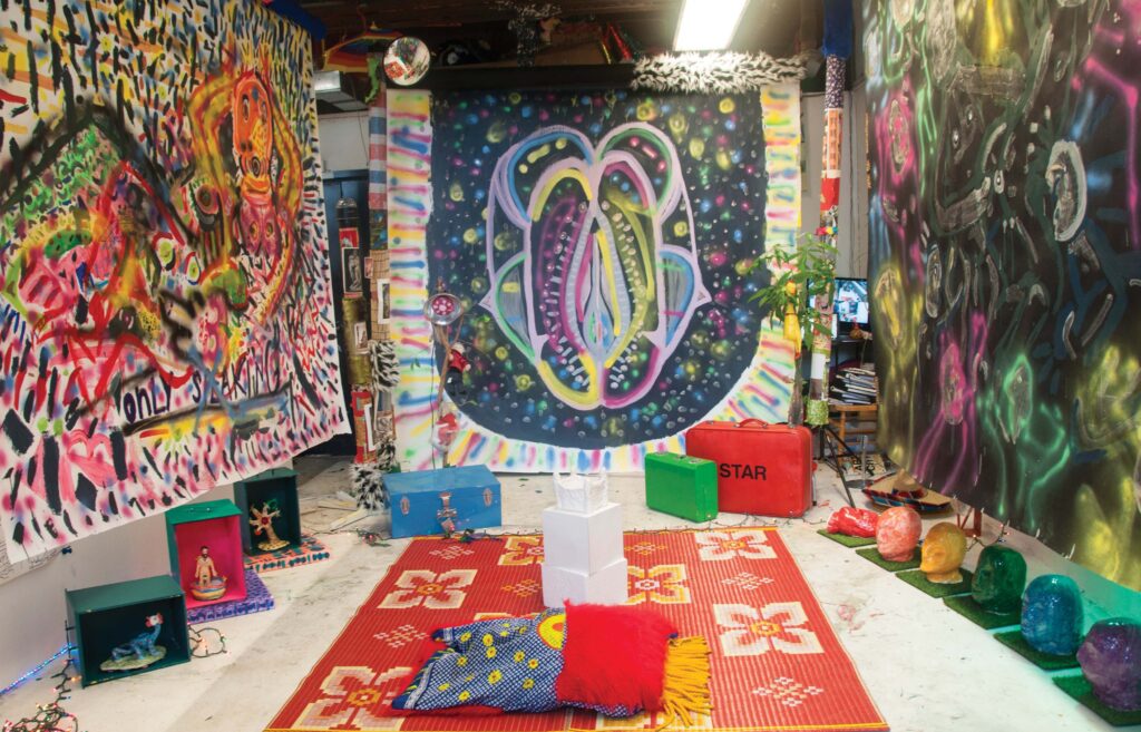 A room with colorfully painted hangings, cushions, and sculptures.