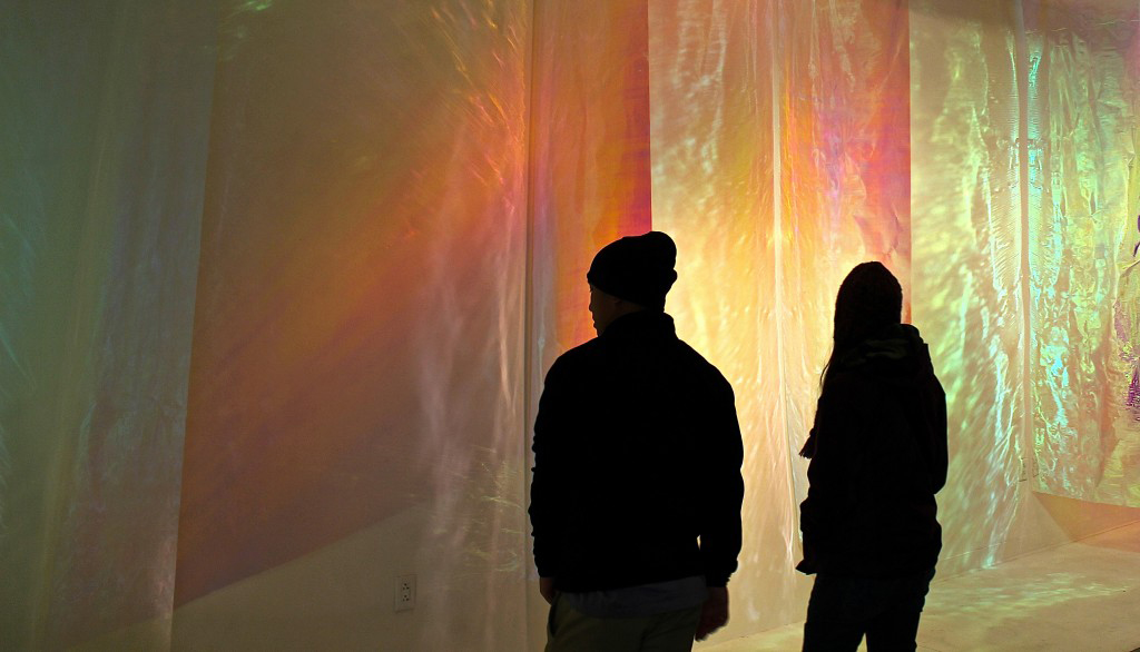 People standing in front of iridescent fabric.