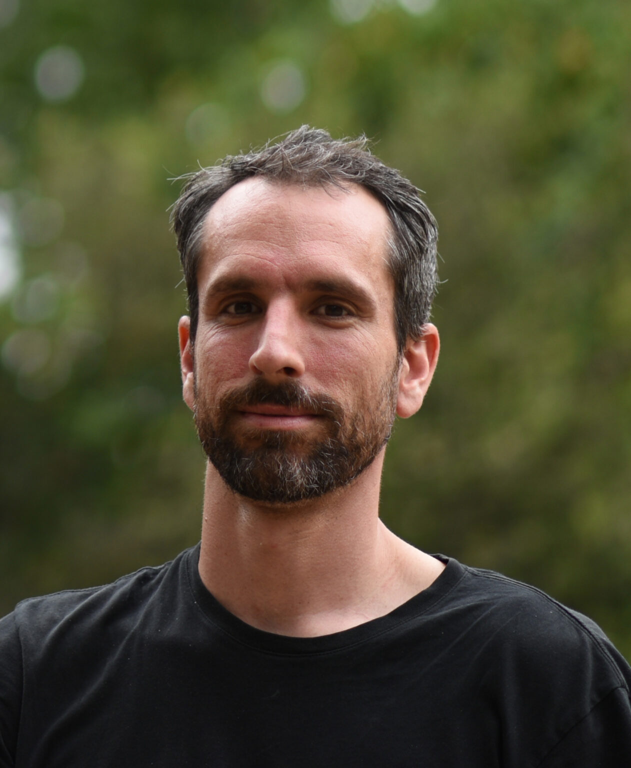 A portrait of a person against a green background.