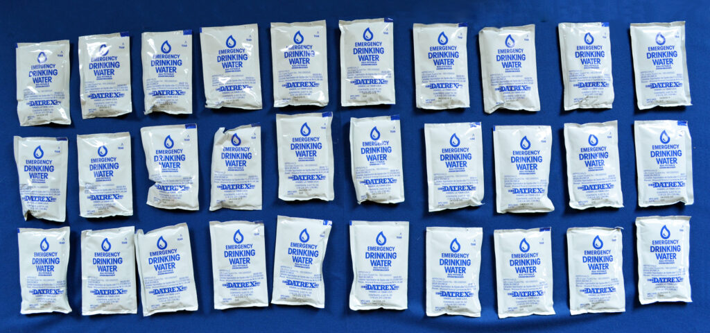 Three rows of plastic emergency water bags against a blue background.