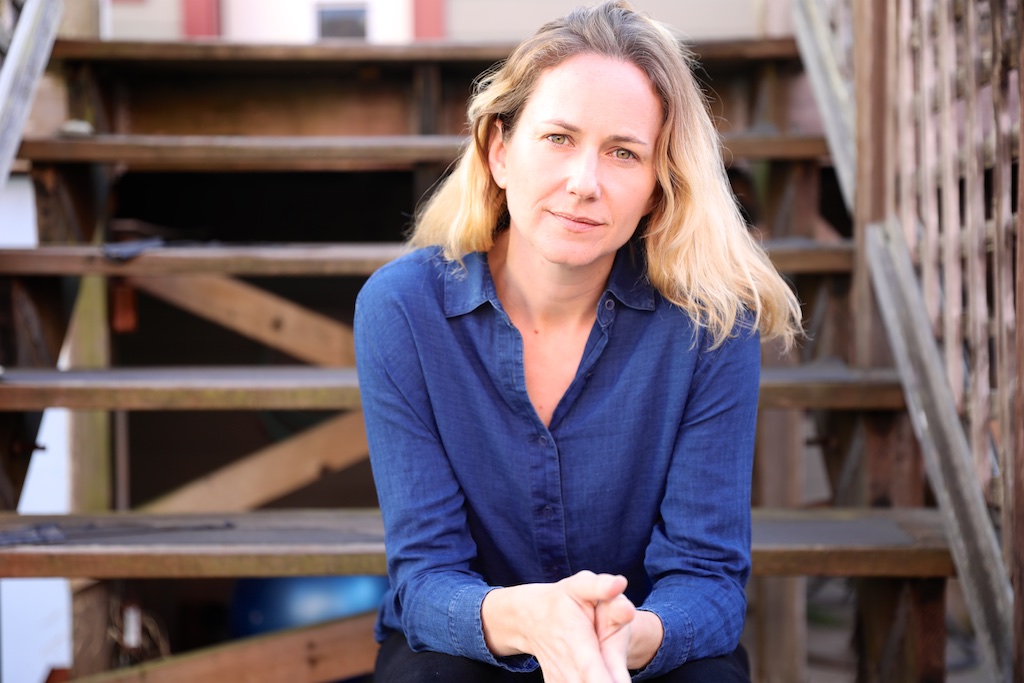 A portrait of a person sitting on wooden stairs.