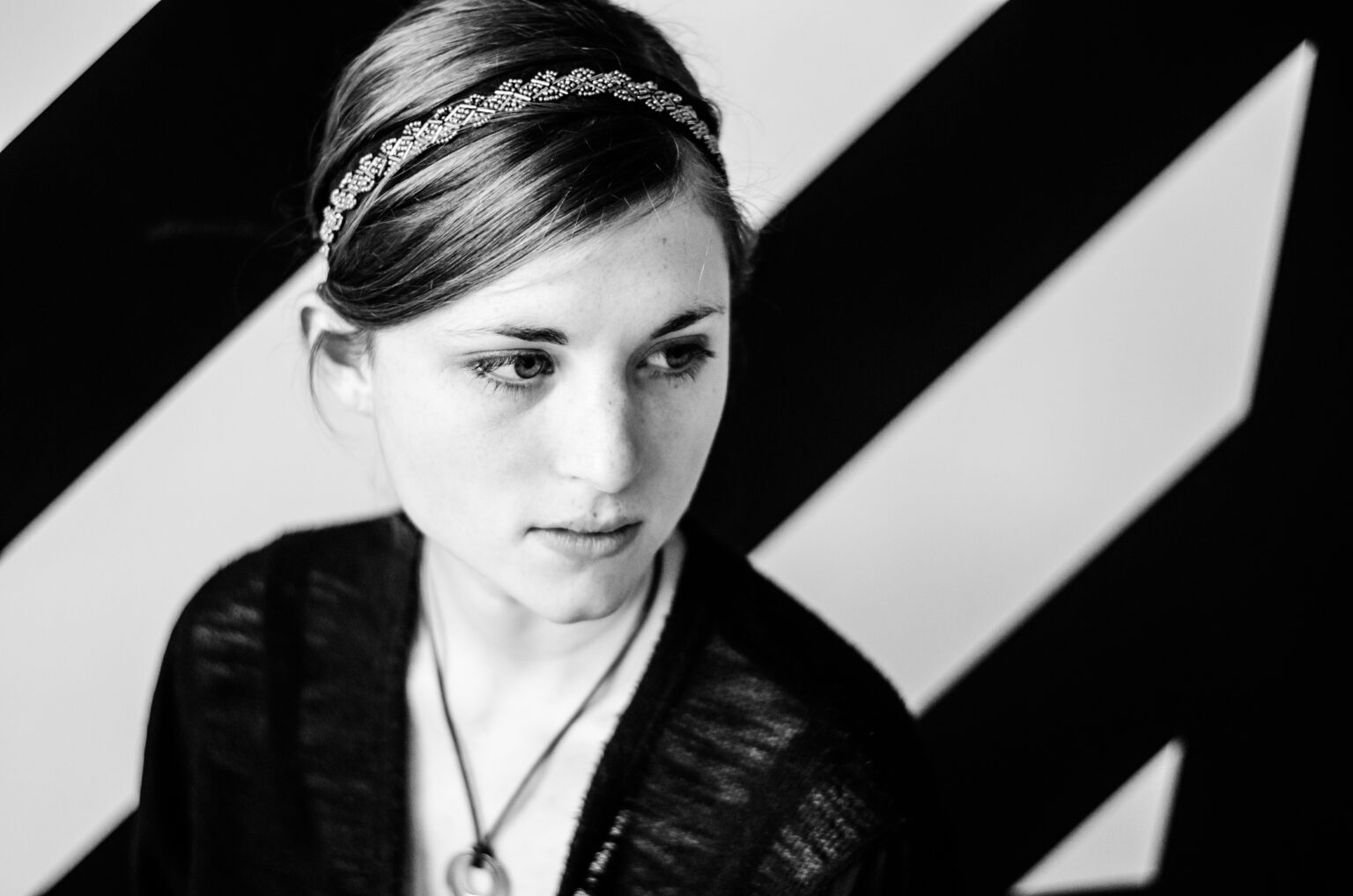 A portrait of a person against a black and white striped background.