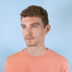 A portrait of a person in front of a light blue background.
