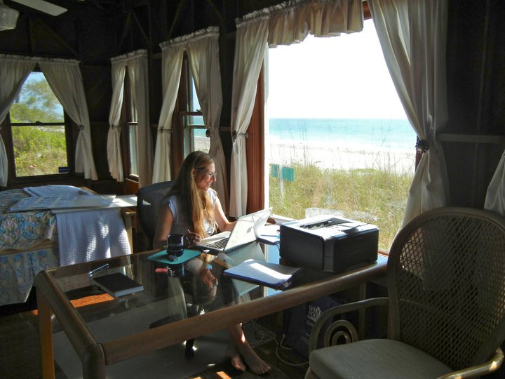 A person sitting at a desk in a house by the ocean.