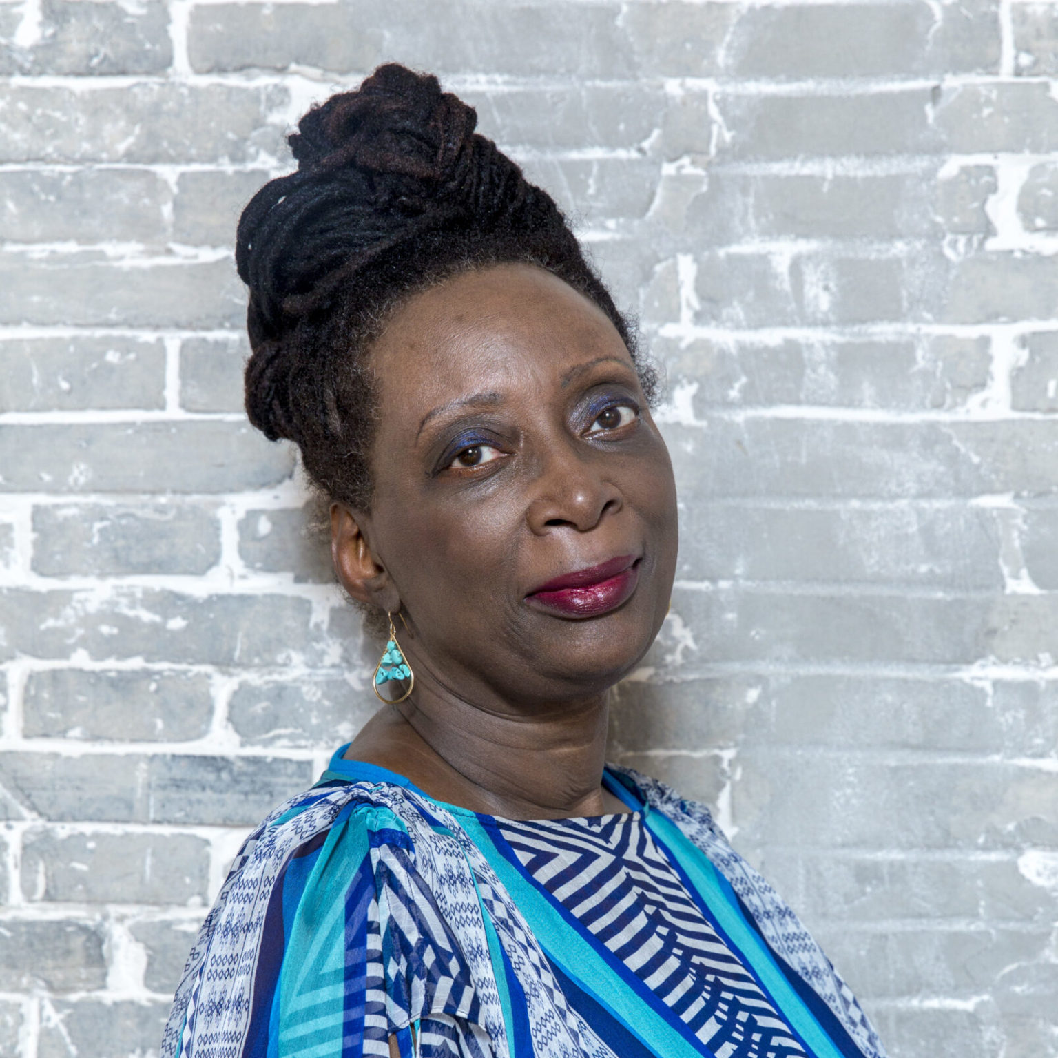 A portrait of person against a brick wall.