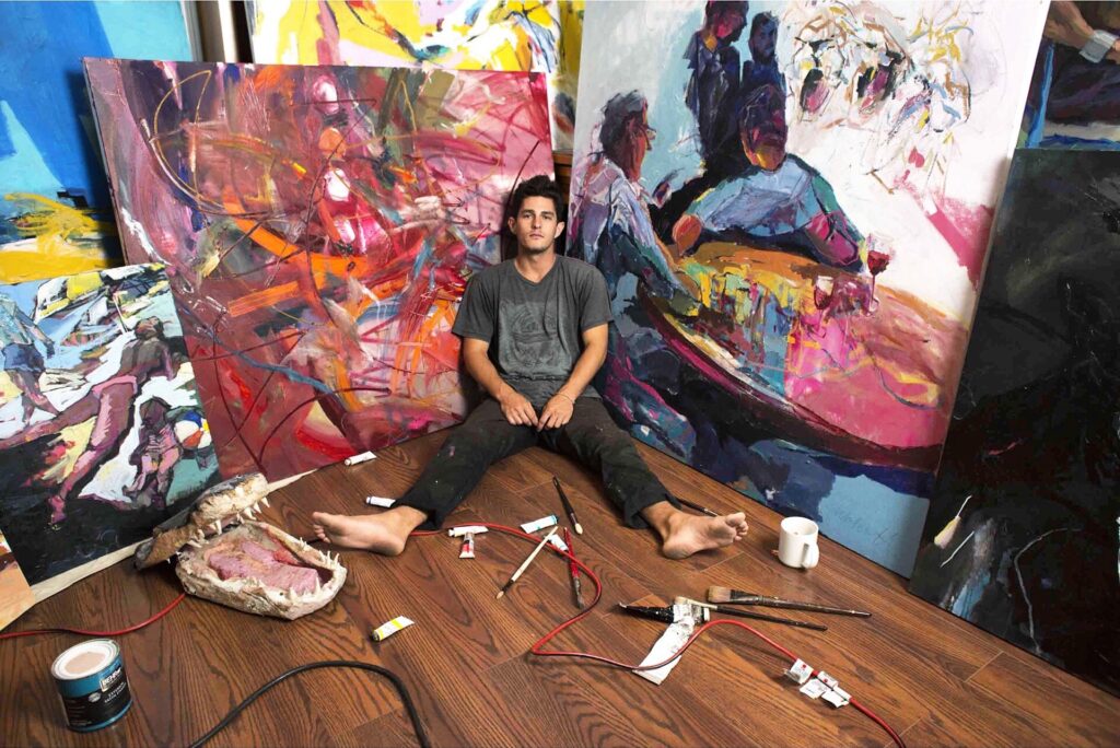 A person sitting on the floor in front of paintings.
