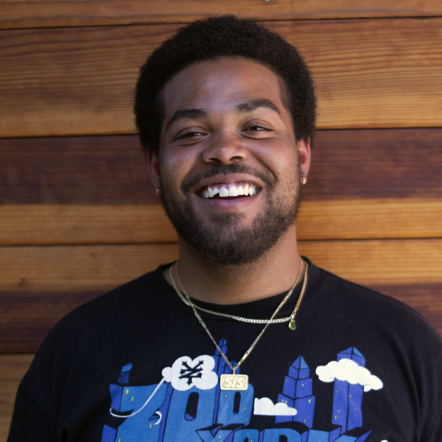 A portrait of a person against a wooden wall.