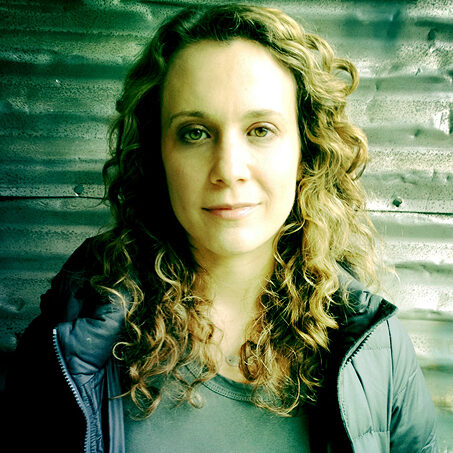 A portrait of person against a corrugated metal wall.