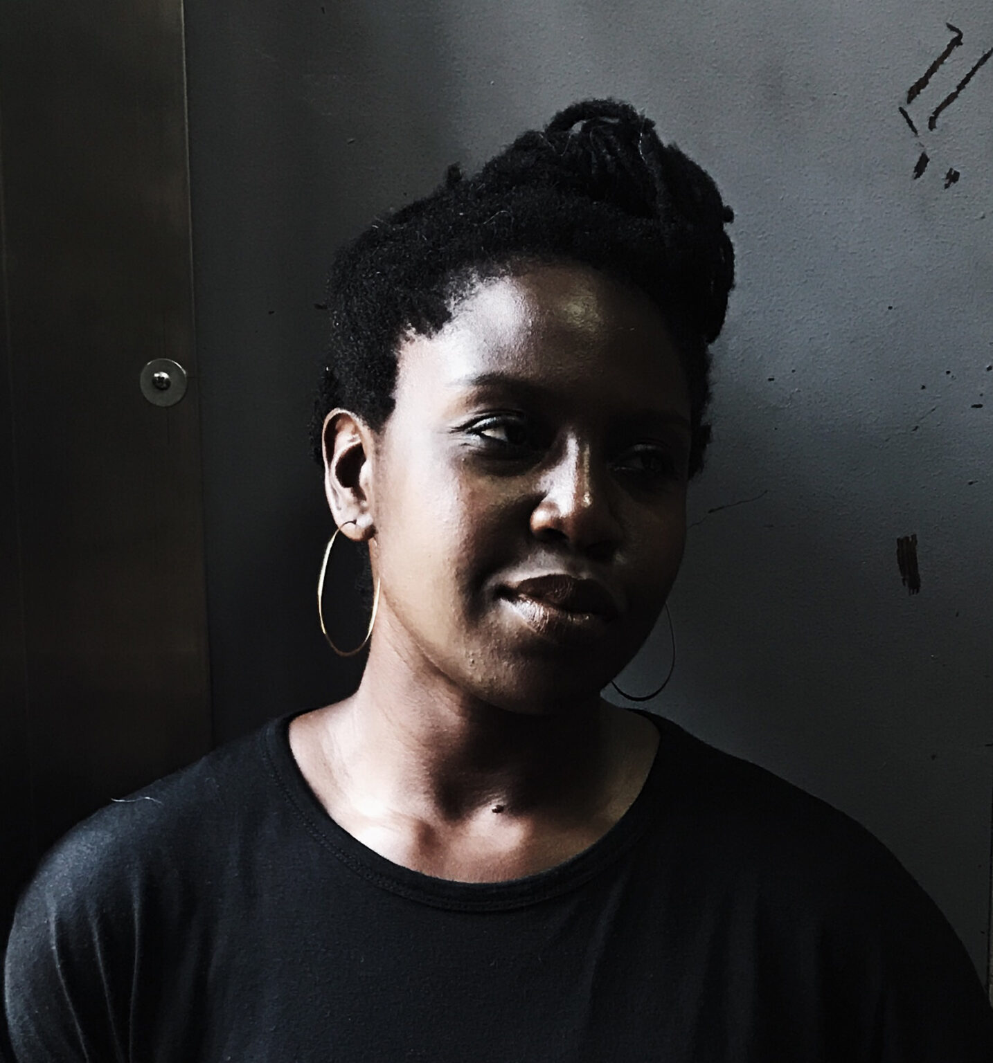 A portrait of a person against a shadowed background.