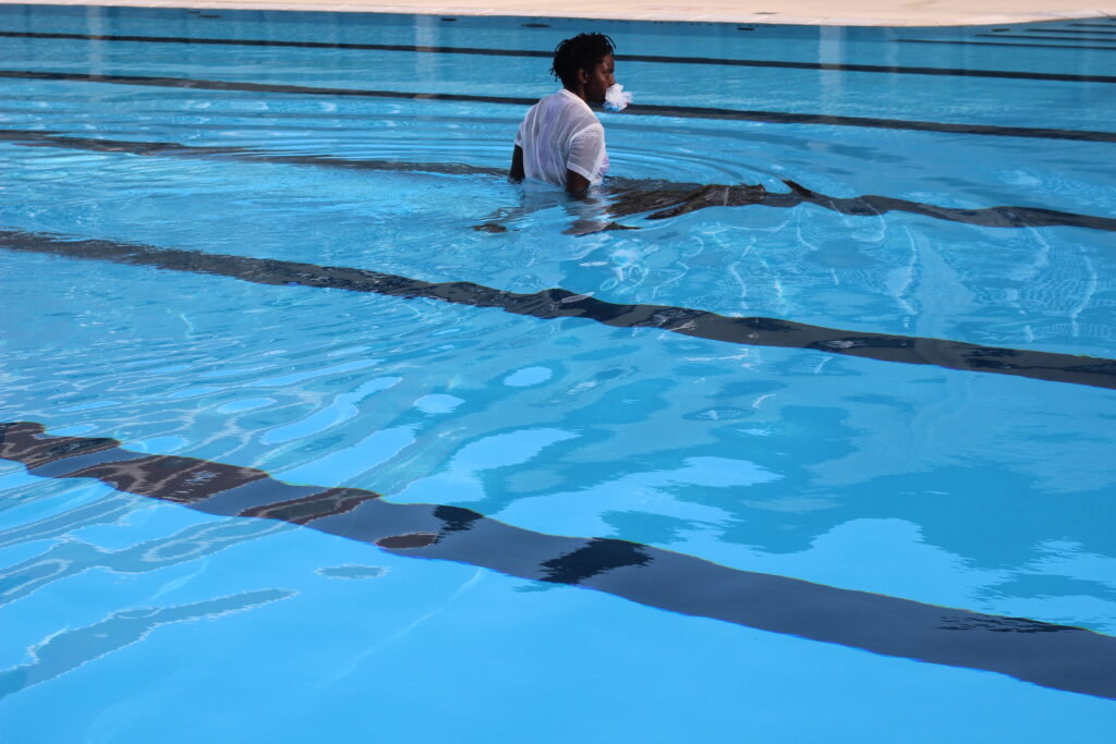 A person in pool with a white material in their mouth.