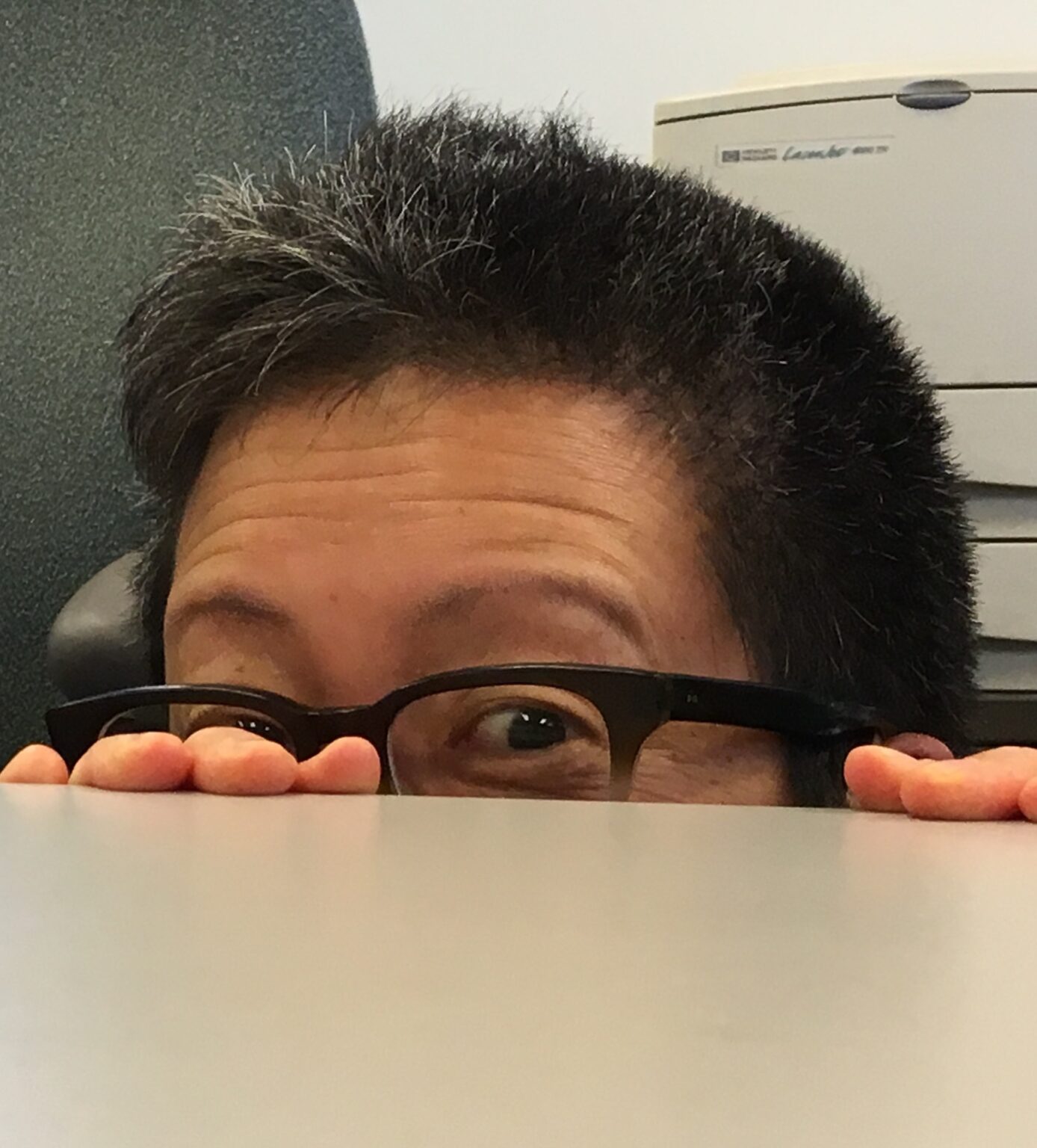 A close-up of a person's eyes peering over a table.