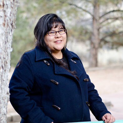 A portrait of a person standing behind a low blue fence.
