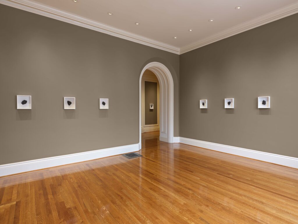A room with small white framed objects on the wall.