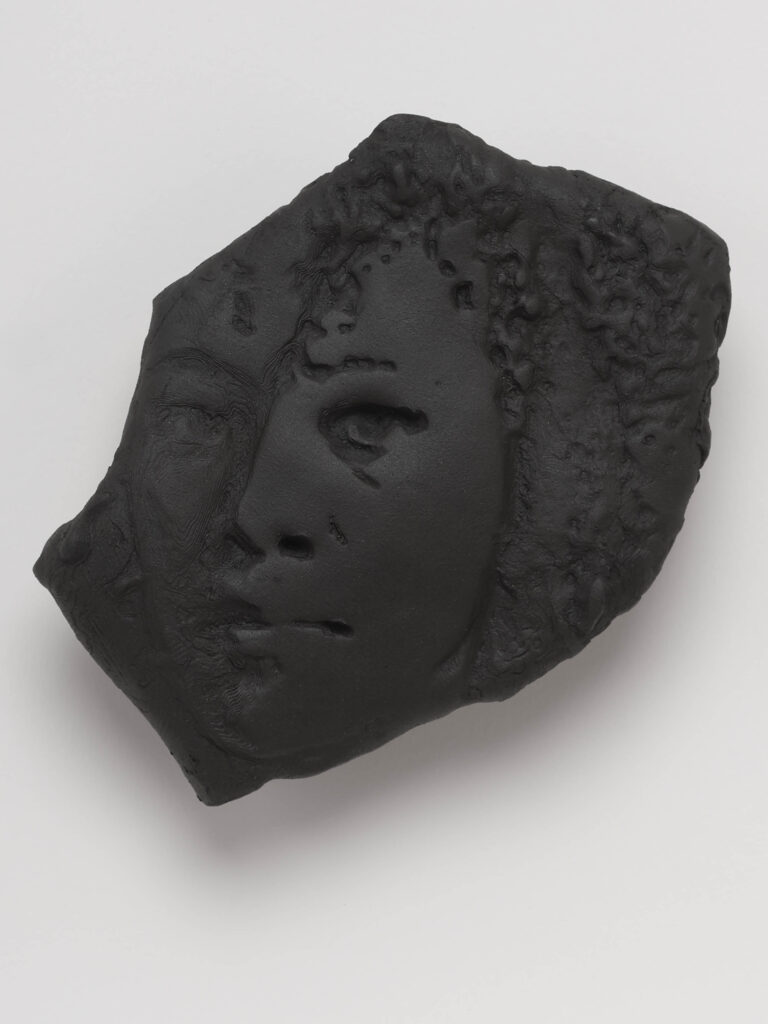 A relief portrait in black clay.
