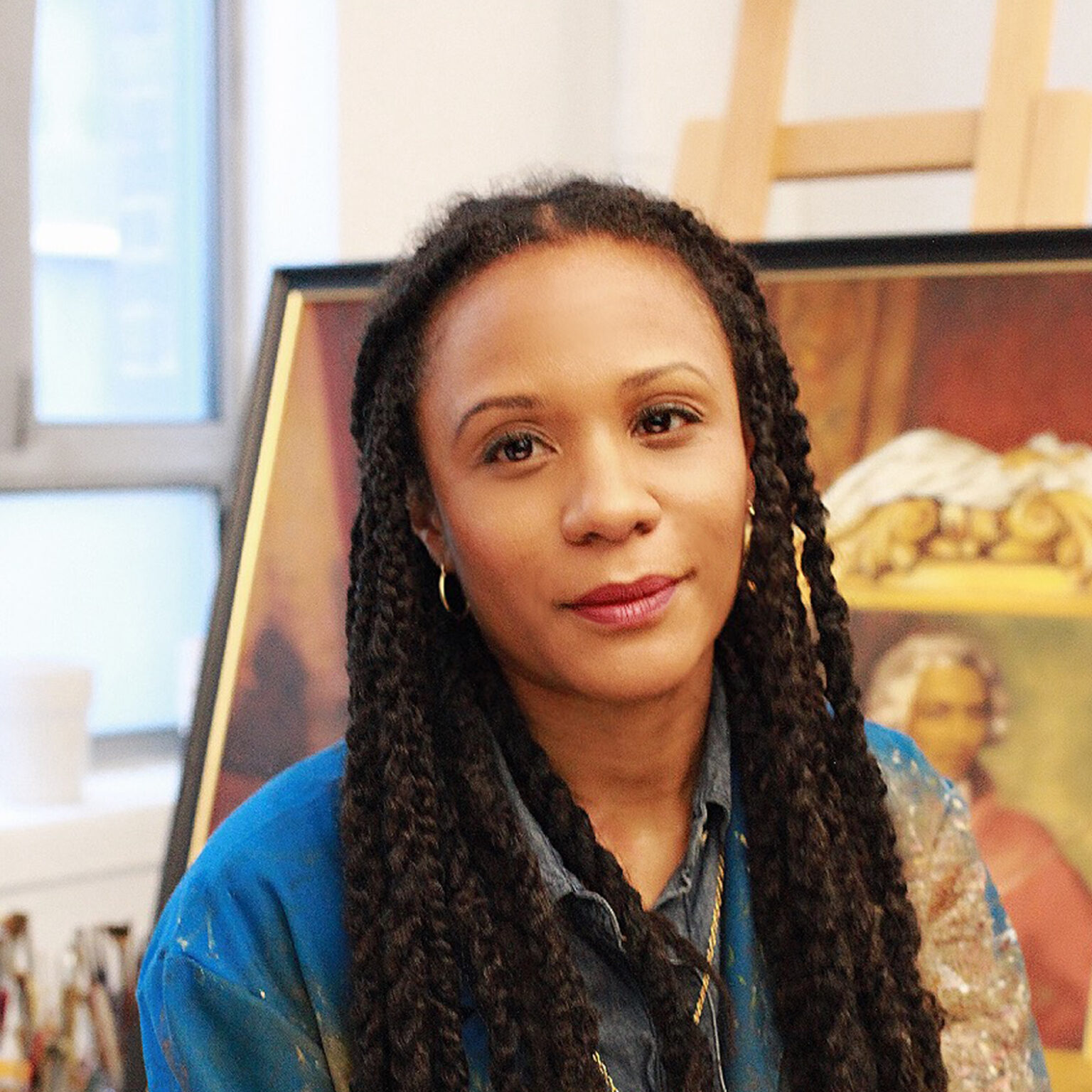 A portrait of a person sitting in front of a canvas on an easel.