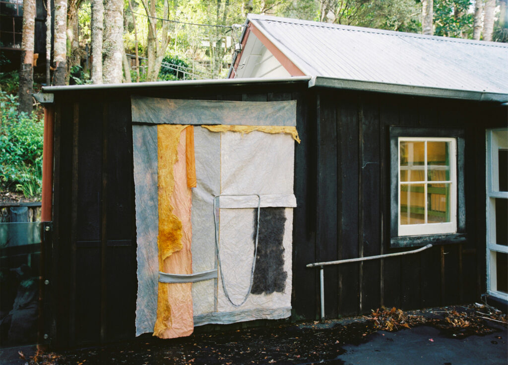 An artwork hung on the side of a small building.