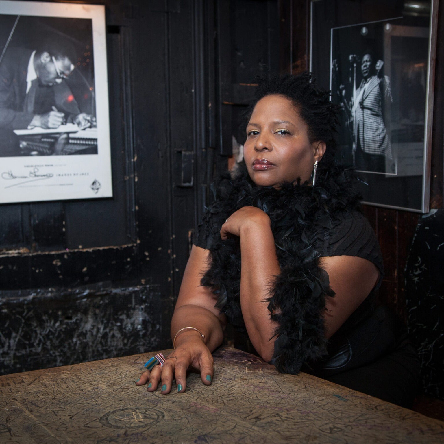 A person sitting at a table in front of framed photographs.