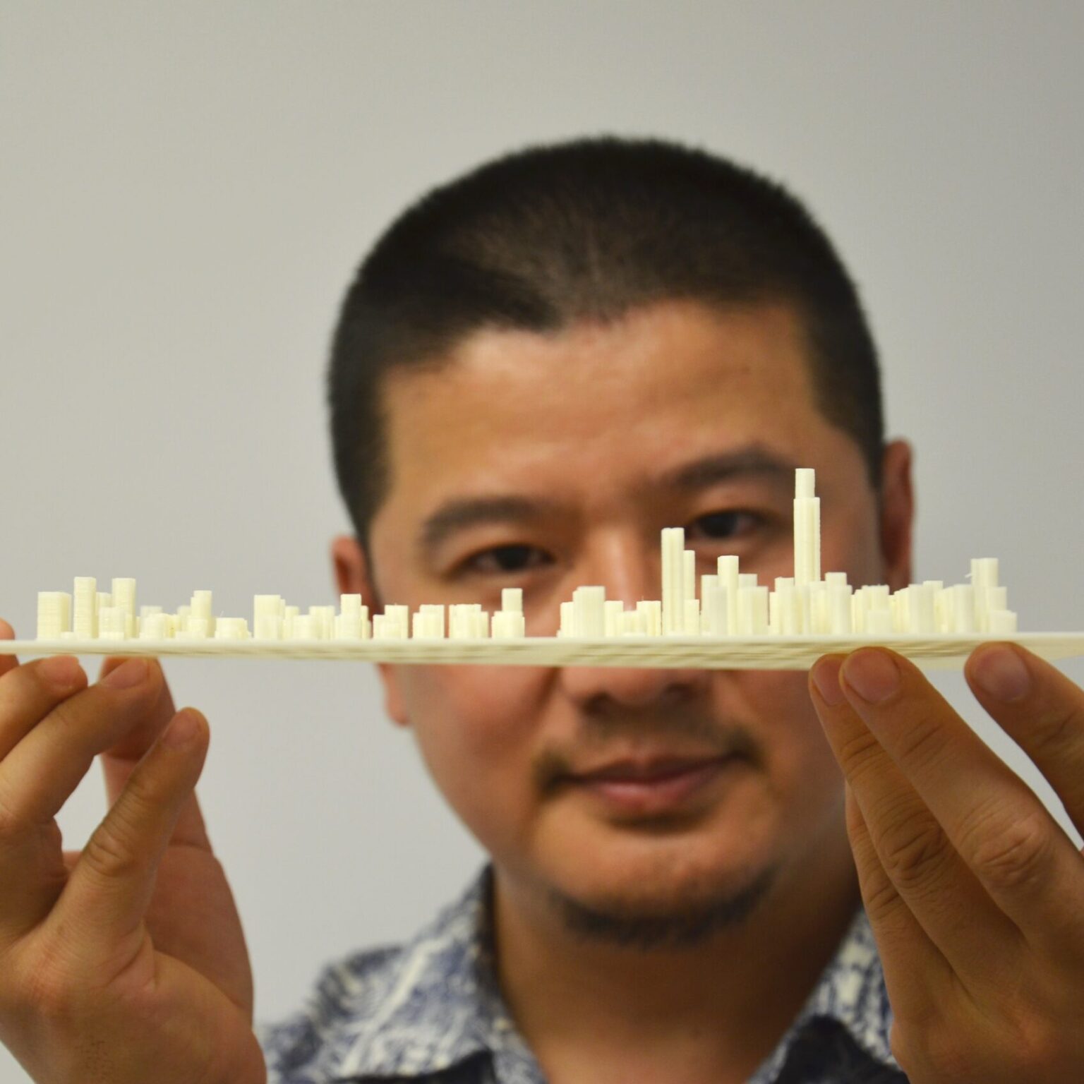 A portrait of a person holding a model of city in front of their face.