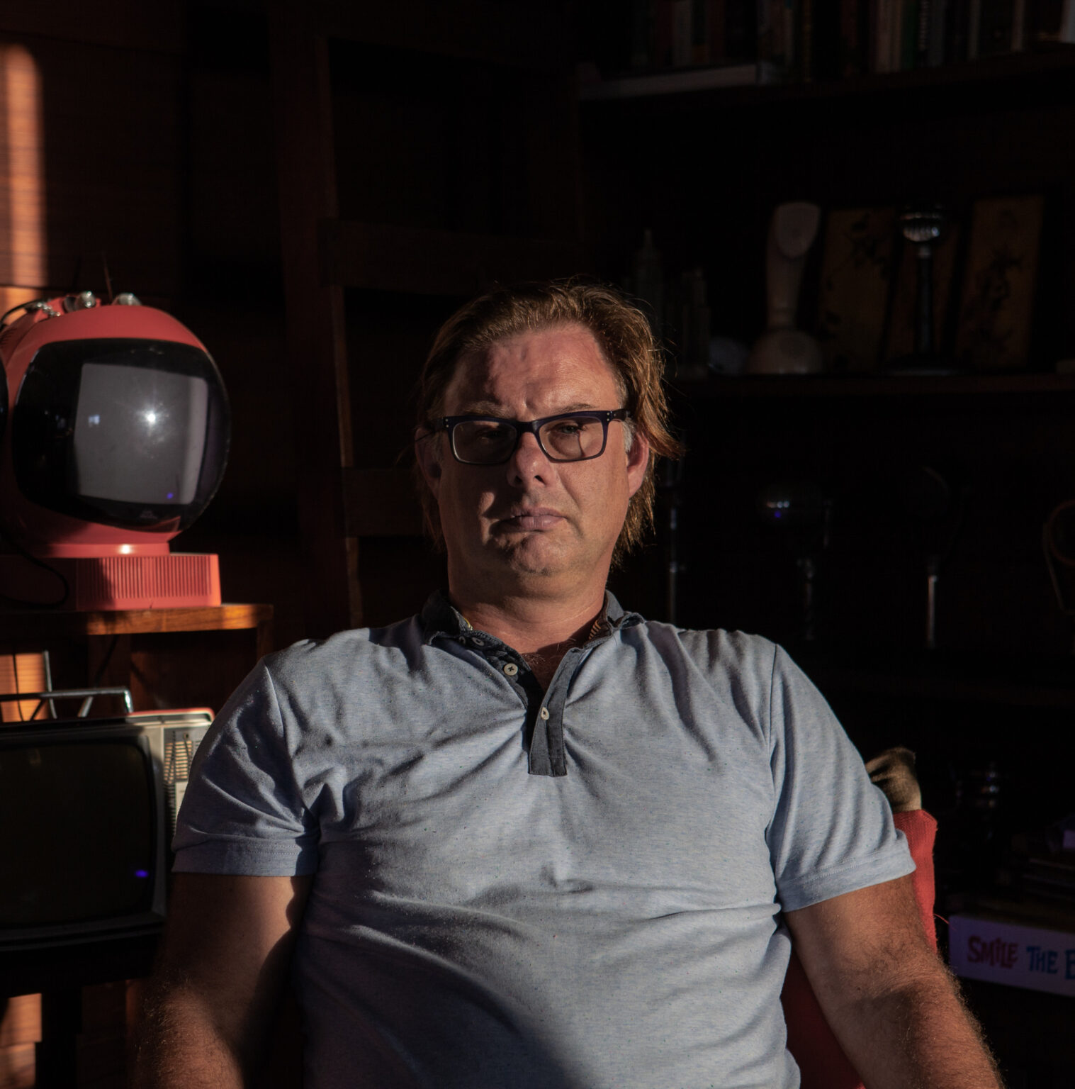 A person sitting in a shadowed room.