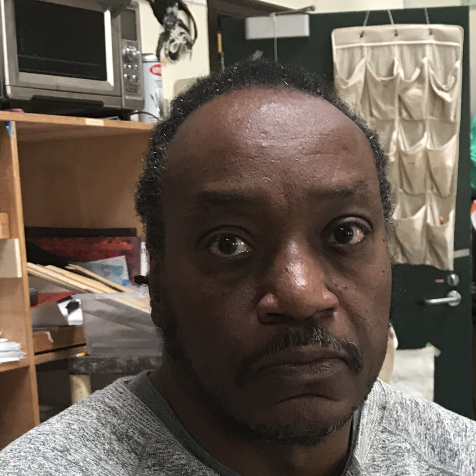 A portrait of a person with a furnished room in the background.