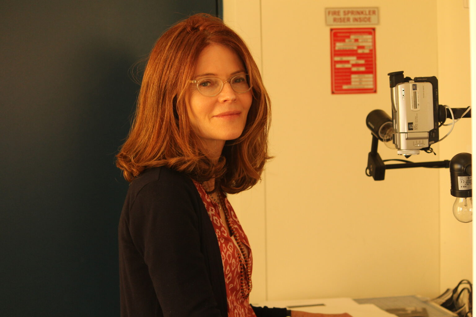 A portrait of a person next to camera equipment.
