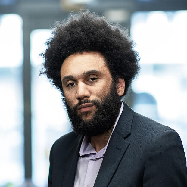 A portrait of a person between two bookshelves.