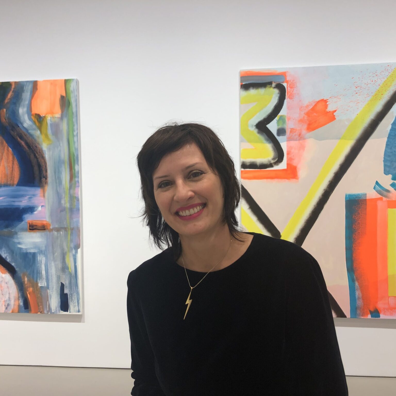 A portrait of a person in front of artworks.