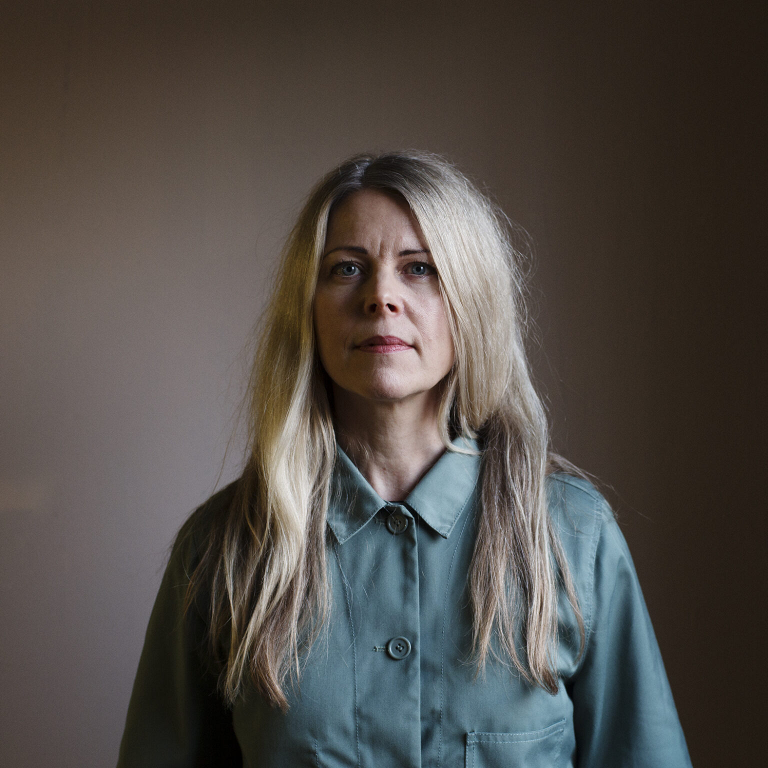 A portrait of a person against a shadowed background.